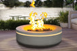 Outdoor concrete fire pit table with bright flames beside a lakeside deck lounge.