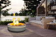 Stylish concrete gas fire pit on timber deck beside cosy outdoor living area at dusk.