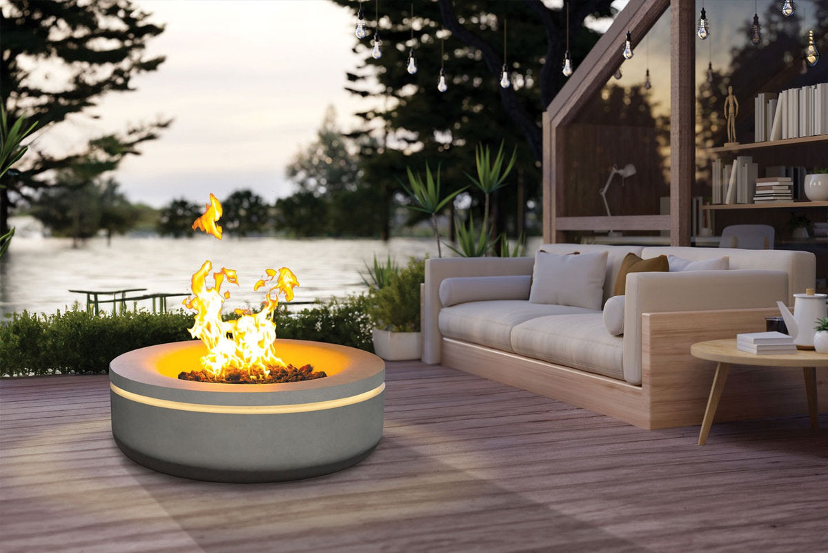 Stylish concrete gas fire pit on timber deck beside cosy outdoor living area at dusk.
