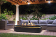 Halo 60 gas fire pit on timber deck surrounded by wicker outdoor furniture at night.