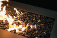 Halo 60 gas fire pit with glass rocks and bright flames in outdoor lounge setting.