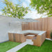 Outdoor patio area with wooden furniture, umbrella, and green grass.