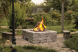 Halo 44 gas fire pit in landscaped garden patio with natural stone paving.


