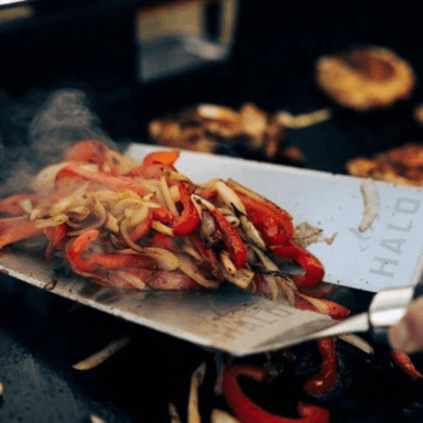 Halo Elite4B Griddle cooking vegetables on the flat top surface with a stainless steel spatula.