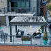 Rooftop terrace featuring a contemporary aluminum pergola with open louvered roof and lounge setup.