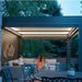 Covered outdoor living area under a black pergola with ambient lighting and comfortable seating.