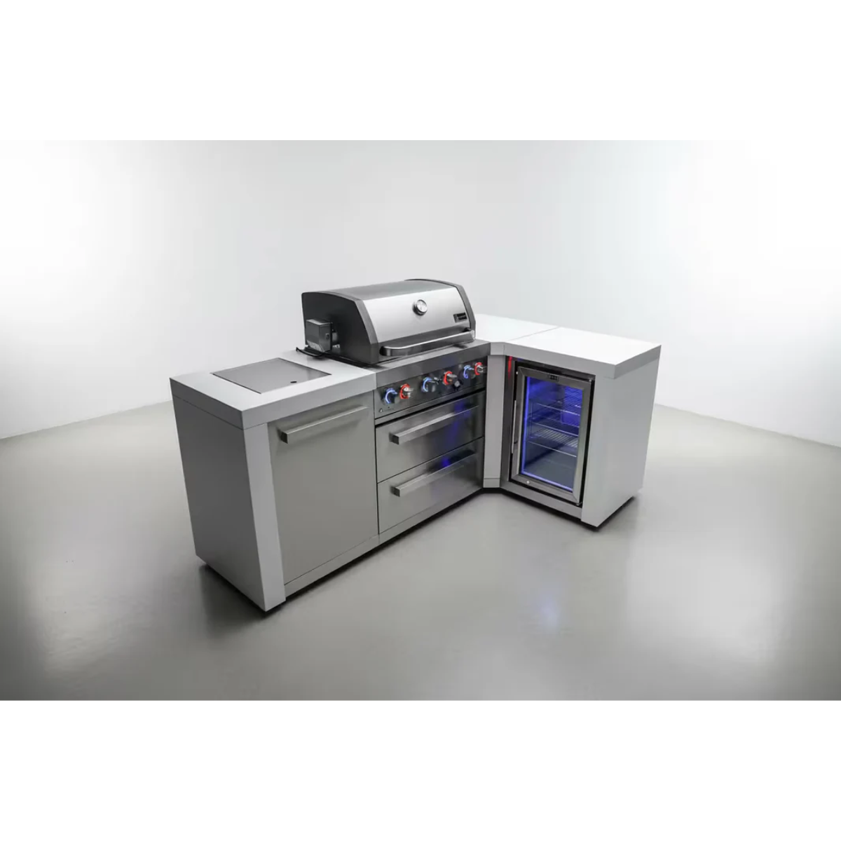 Angled view of the Mont Alpi 400 Deluxe Island with 90-degree corner, built-in gas grill, fridge cabinet, storage door, and illuminated outdoor refrigerator.