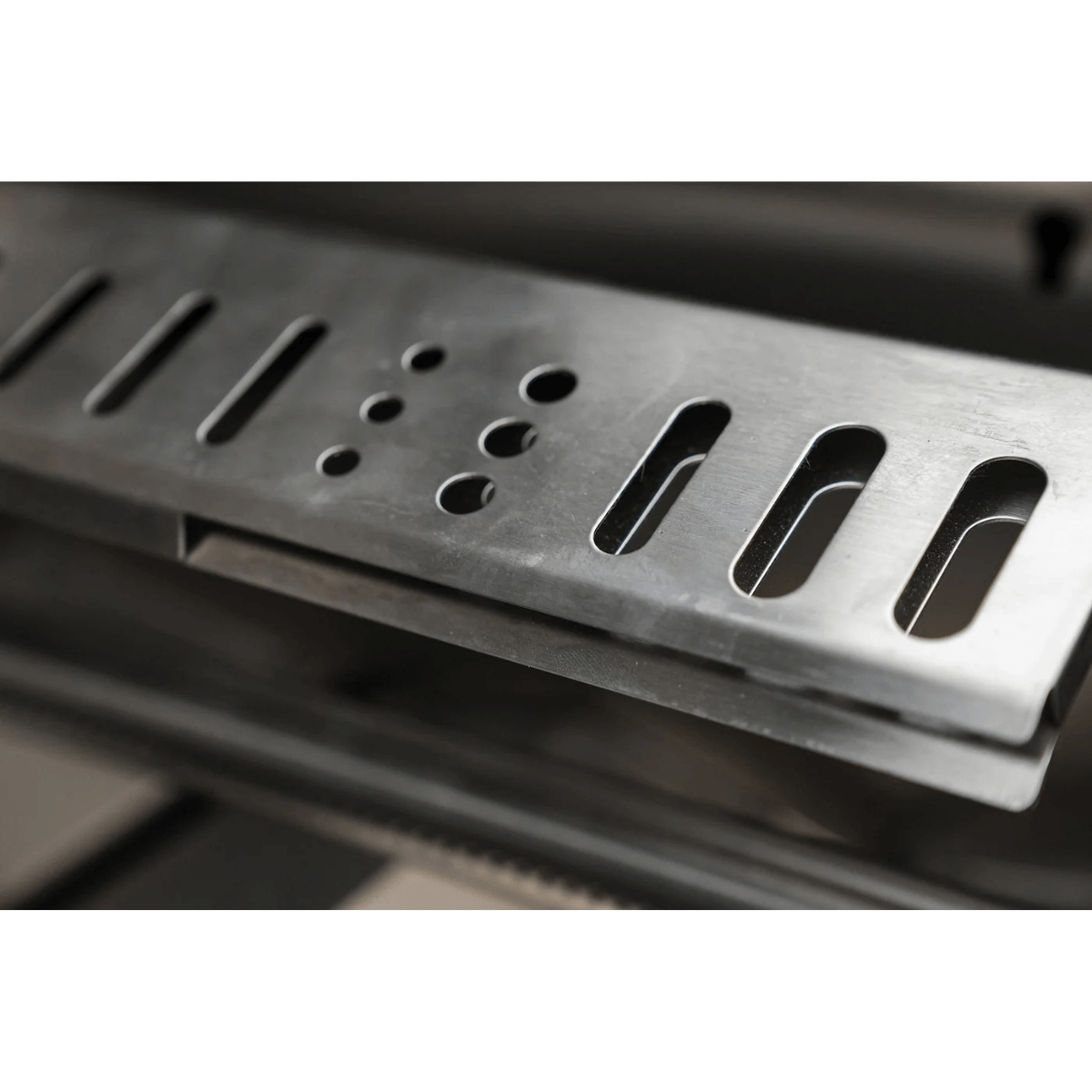 Close-up of the Mont Alpi 44-Inch Built-In Grill flame tamers, showing stainless steel heat distribution plates beneath the cooking grates.