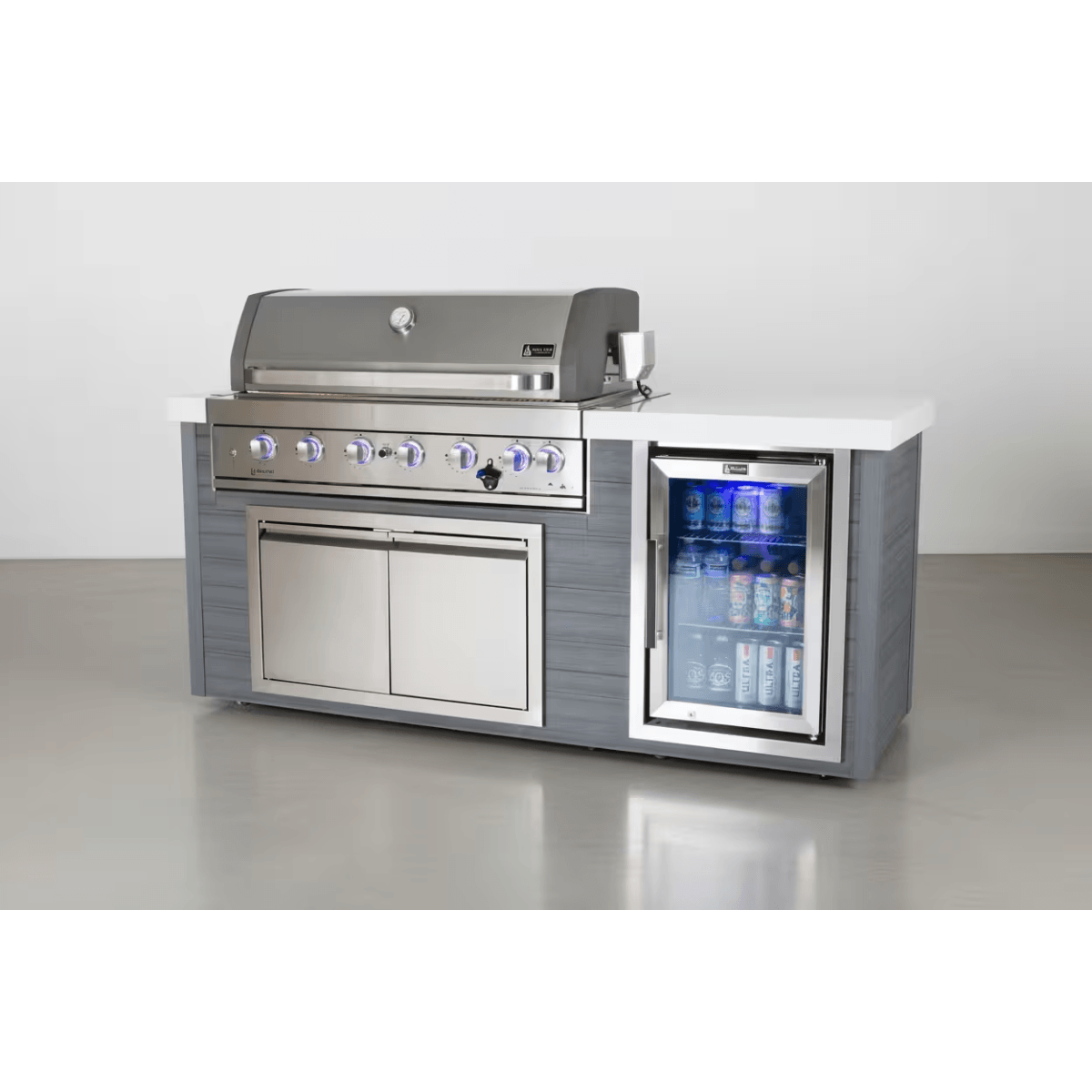 Studio view of the Mont Alpi 6-Burner Stainless Steel Art-wood Outdoor Island Grill with closed hood, storage cabinet, and built-in glass-door beverage fridge.
