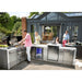 Outdoor entertaining scene featuring the Mont Alpi 805 Deluxe Island with 90-degree corner, kegerator, beverage center, and guests gathered around the grill.