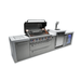 Angled view of the Mont Alpi 805 Deluxe Island with the grill hood open, highlighting the cooking surface, LED-lit control knobs, kegerator, and fridge cabinet.