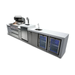 Front-right angled view of the Mont Alpi 805 Deluxe Island with the grill lid open, highlighting the outdoor kitchen layout, beverage center, sink, and dual glass-door refrigerators.