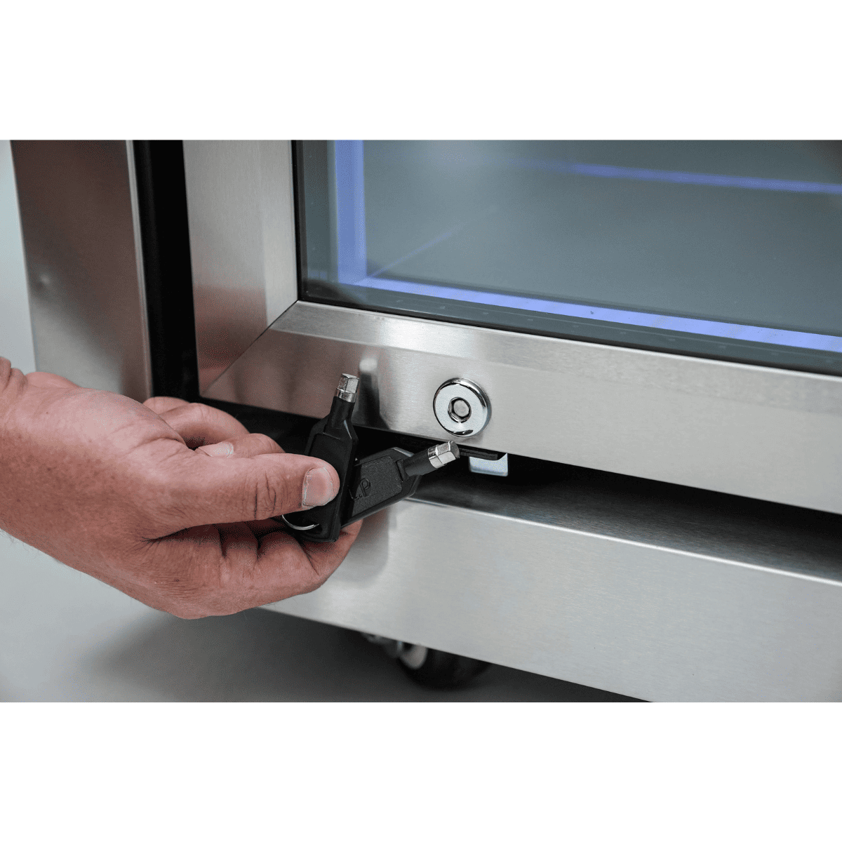 Close-up of the Mont Alpi Black Stainless Steel Fridge Cabinet Module lock with a key being inserted into the stainless steel glass door.