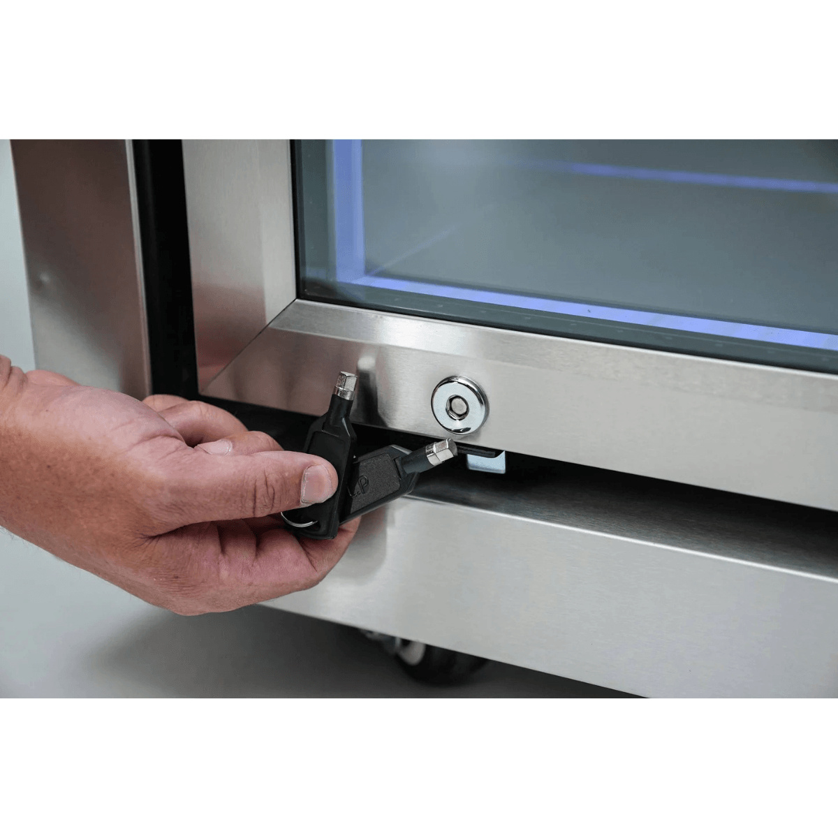 Close-up of the Mont Alpi outdoor fridge lock and key system on a stainless steel glass door for secure beverage storage.