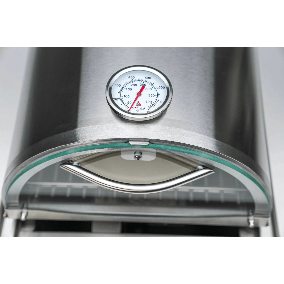 Close-up of the Mont Alpi universal side burner pizza oven showing the built-in temperature gauge and curved glass door handle.