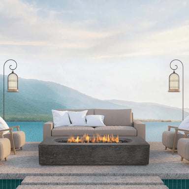 Dark grey Pyromania Alchemy fire table with active flames in a luxury outdoor seating setup.