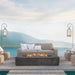 Dark grey Pyromania Alchemy fire table with active flames in a luxury outdoor seating setup.