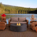 Avalon concrete fire pit with wicker patio furniture beside a lakeside outdoor setting.