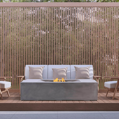Pyromania Moderne fire table with outdoor lounge seating and wood privacy screen backdrop.