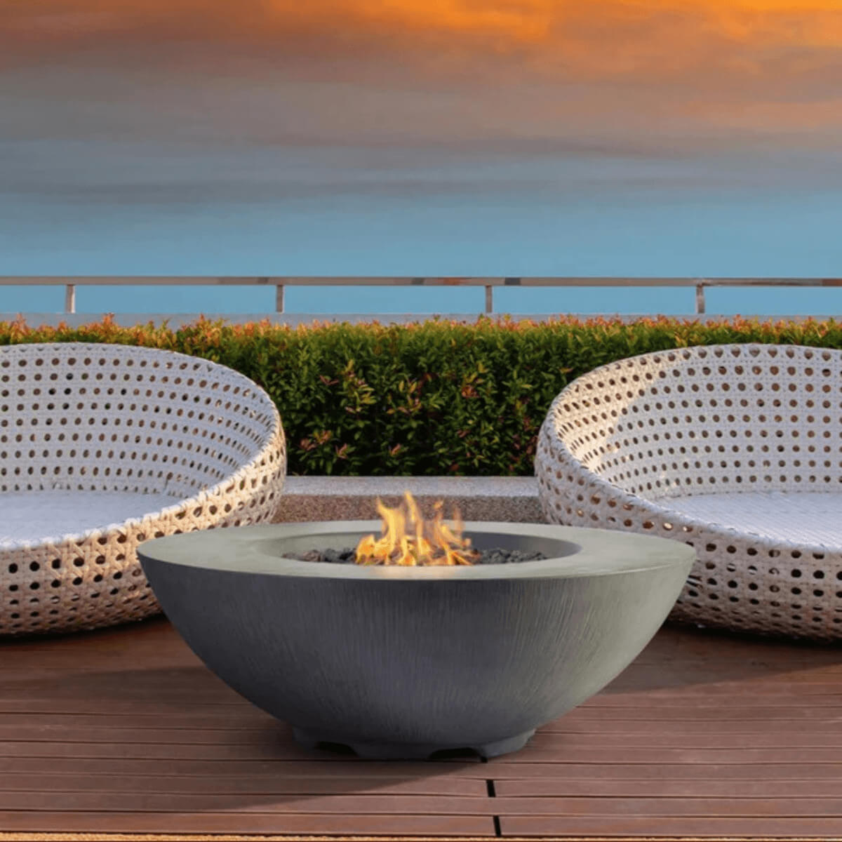 Pyromania Shangri-La fire table displayed on an outdoor deck between woven lounge chairs.