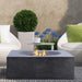 Pyromania Tao concrete fire table with outdoor lounge chairs and modern patio setting.