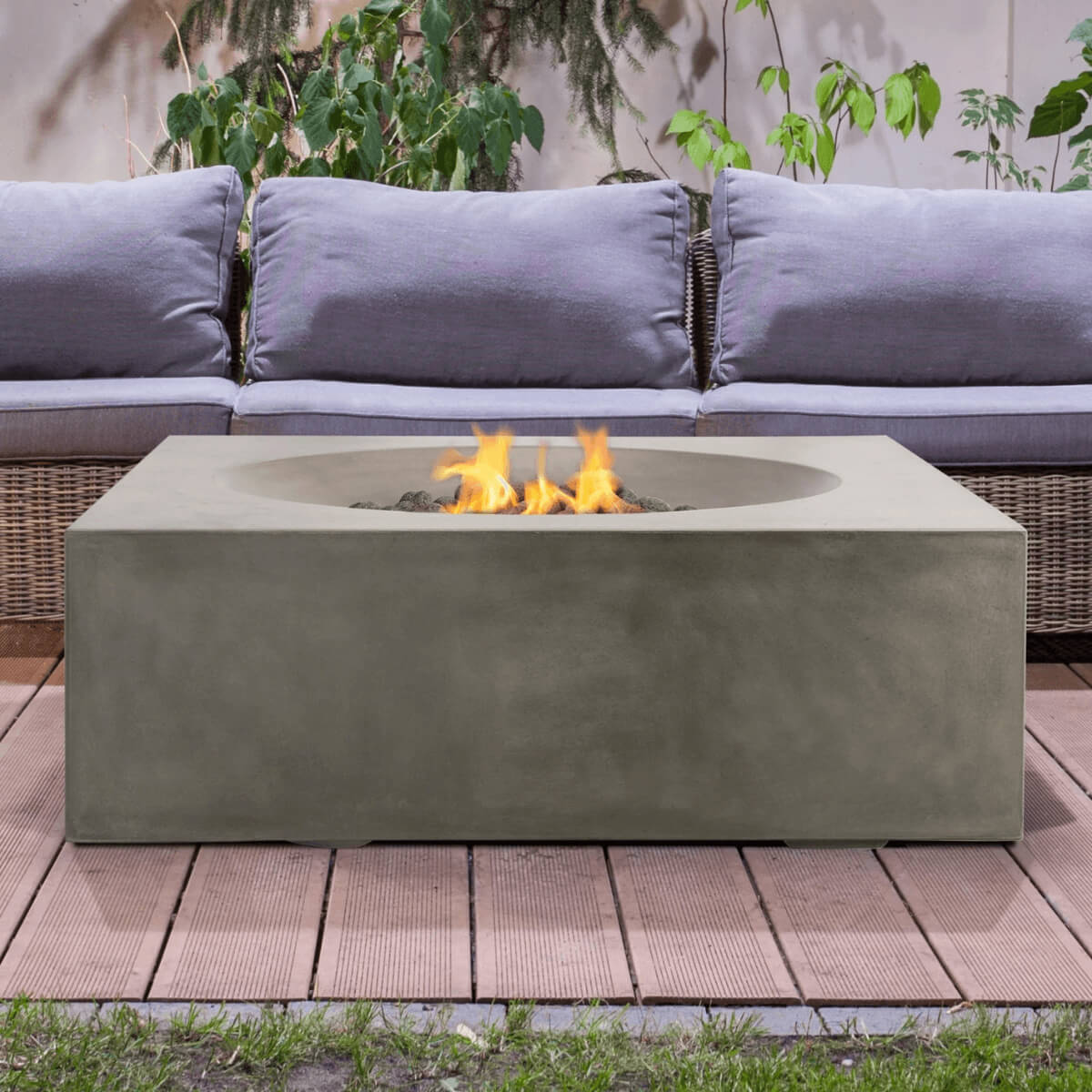 Pyromania Tao concrete fire table with wicker sofa seating and active gas flames.